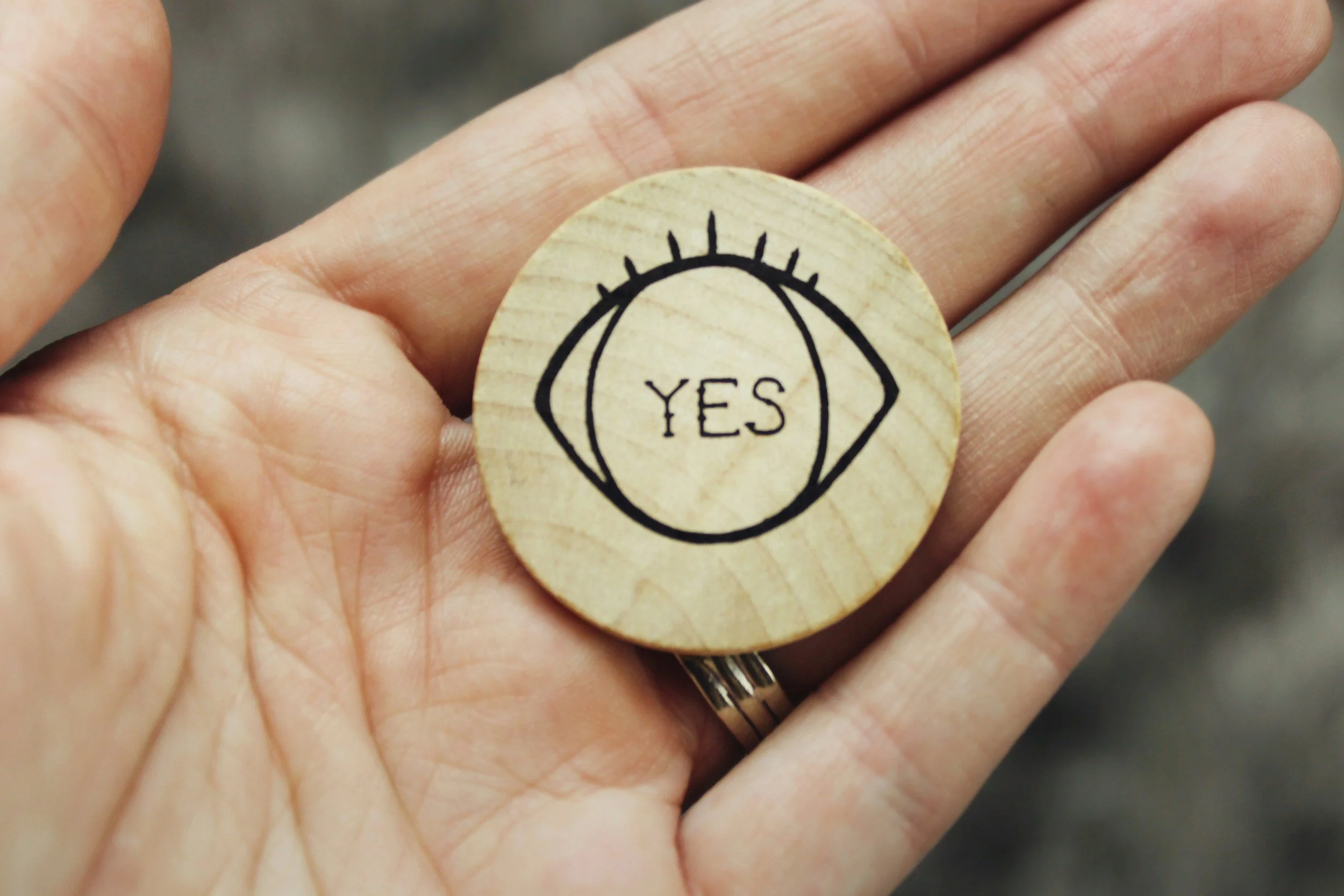 hand holding a round object with an eye and the word "yes"