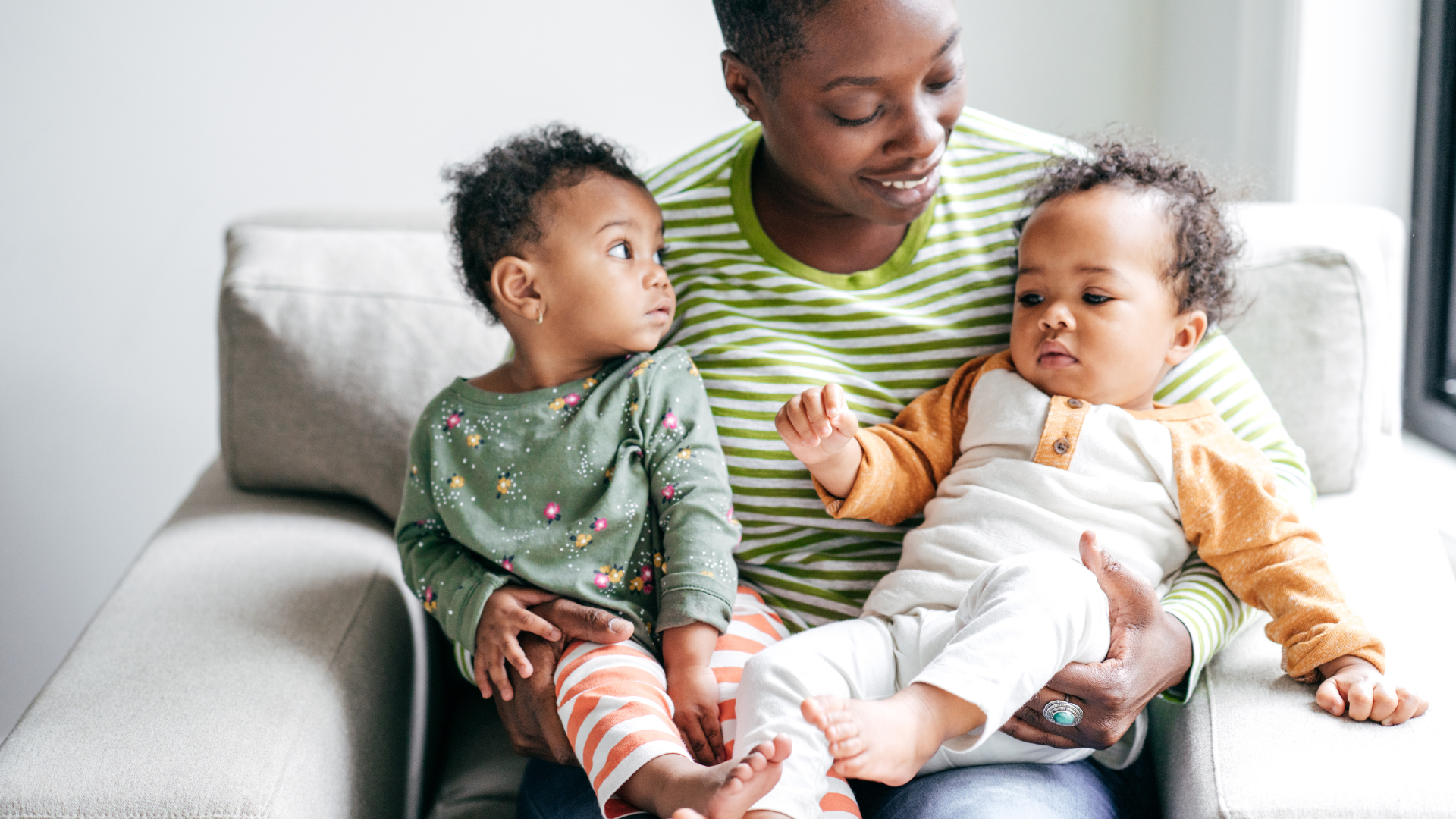 black woman sitting in a chair with two babies