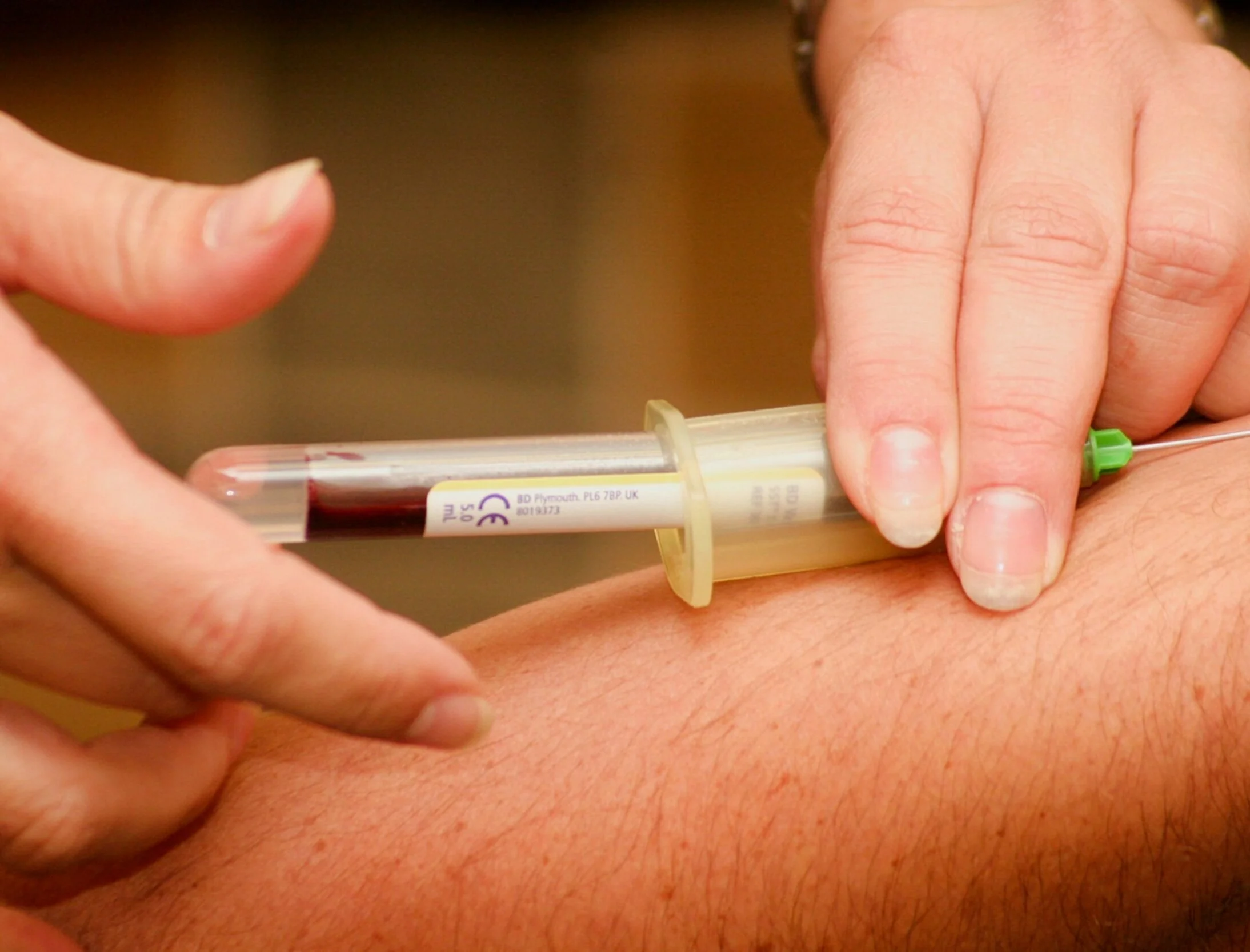 Person administering an injection with a syringe into another person's arm.