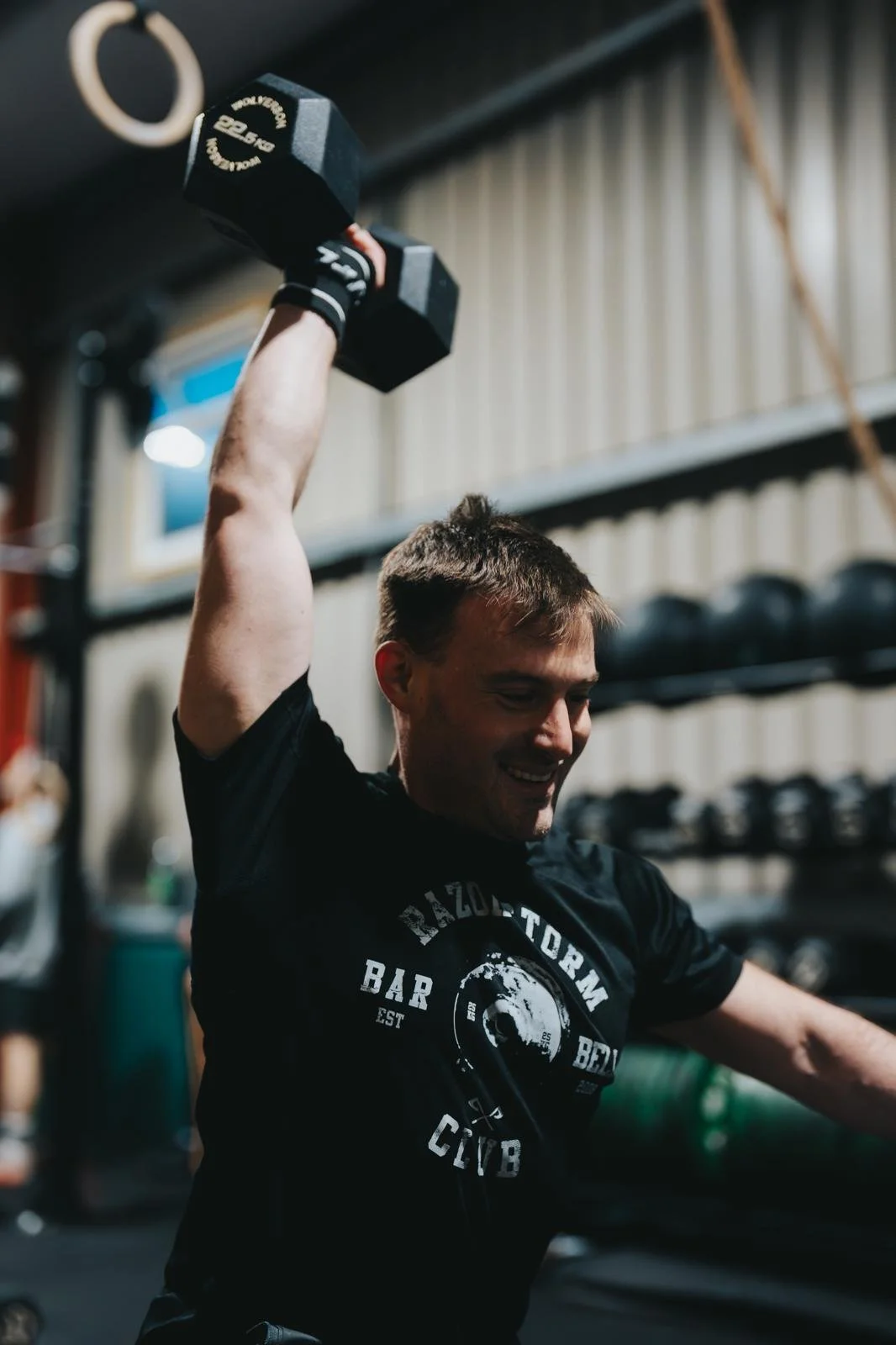 A photo of head coach Gideon lifting a dumbbell in a gym.