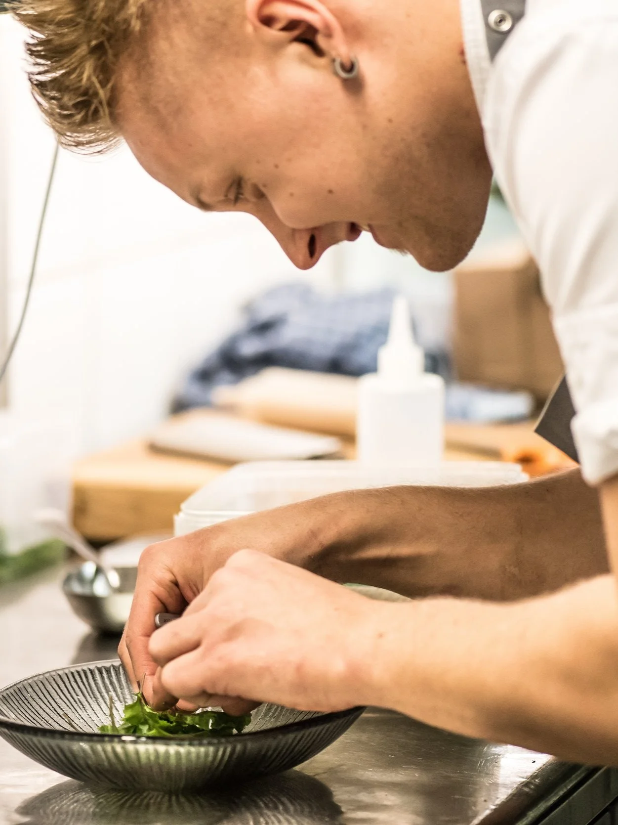 A person focused on preparing a dish with fresh herbs on a kitchen countertop.
