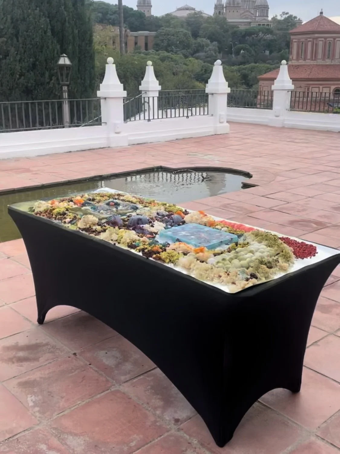 A table decorated with candles and flowers on a rooftop terrace with a cityscape in the background.