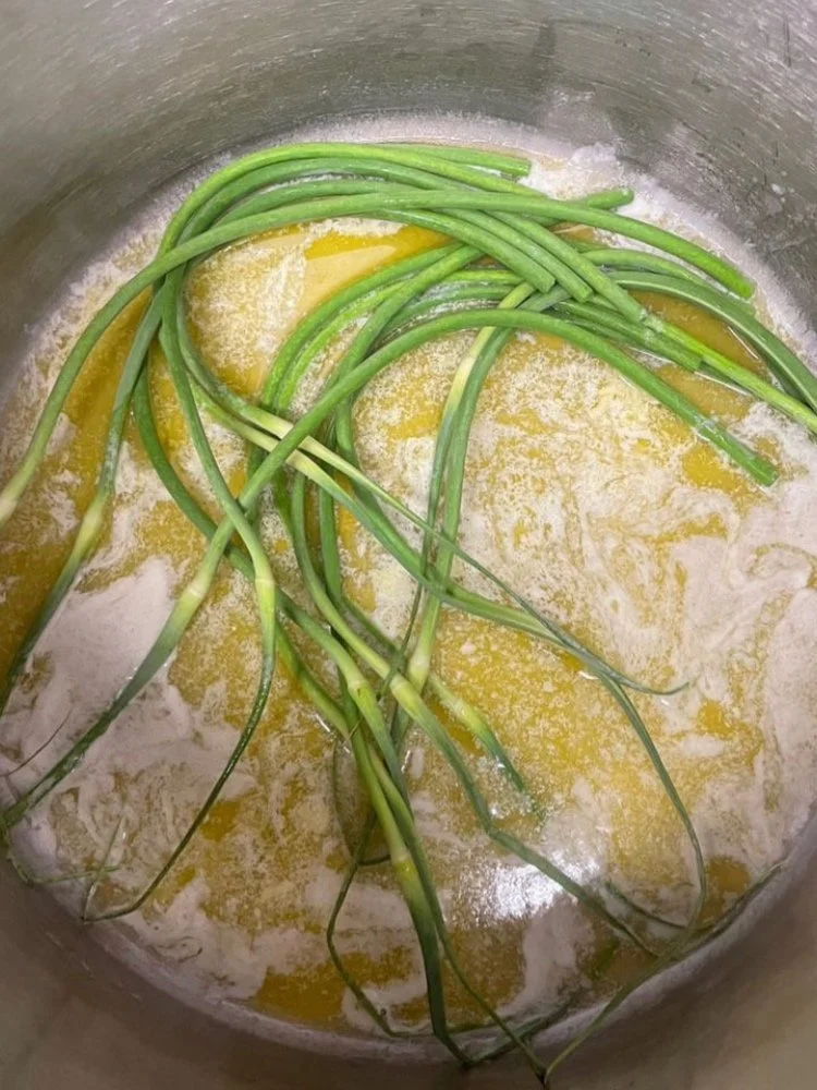 Green onions cooking in a pot with butter or oil and flour.