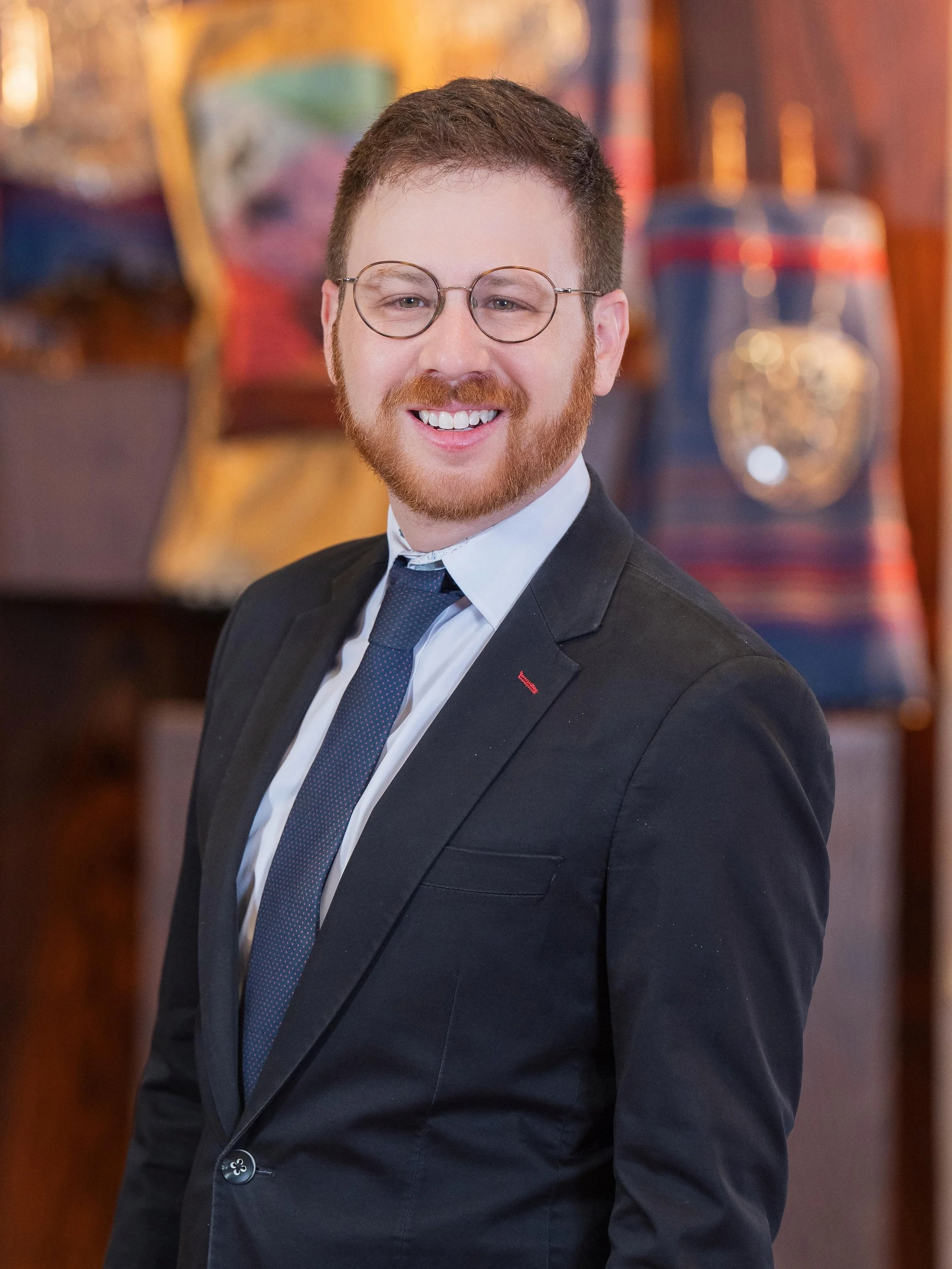 Cantor Lerhman in a dark suit in front of a gray background.
