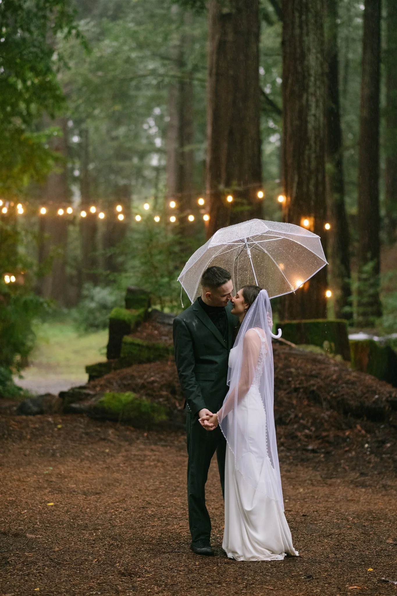 documentary-style-couple-kissing-under-clear-umbrella-forest-ceremony.jpg