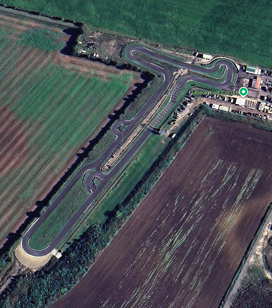 Aerial view of Fulbeck Kart Circuit, a go-kart racing track with sharp turns and long straightaways, surrounded by agricultural fields and a parking area.