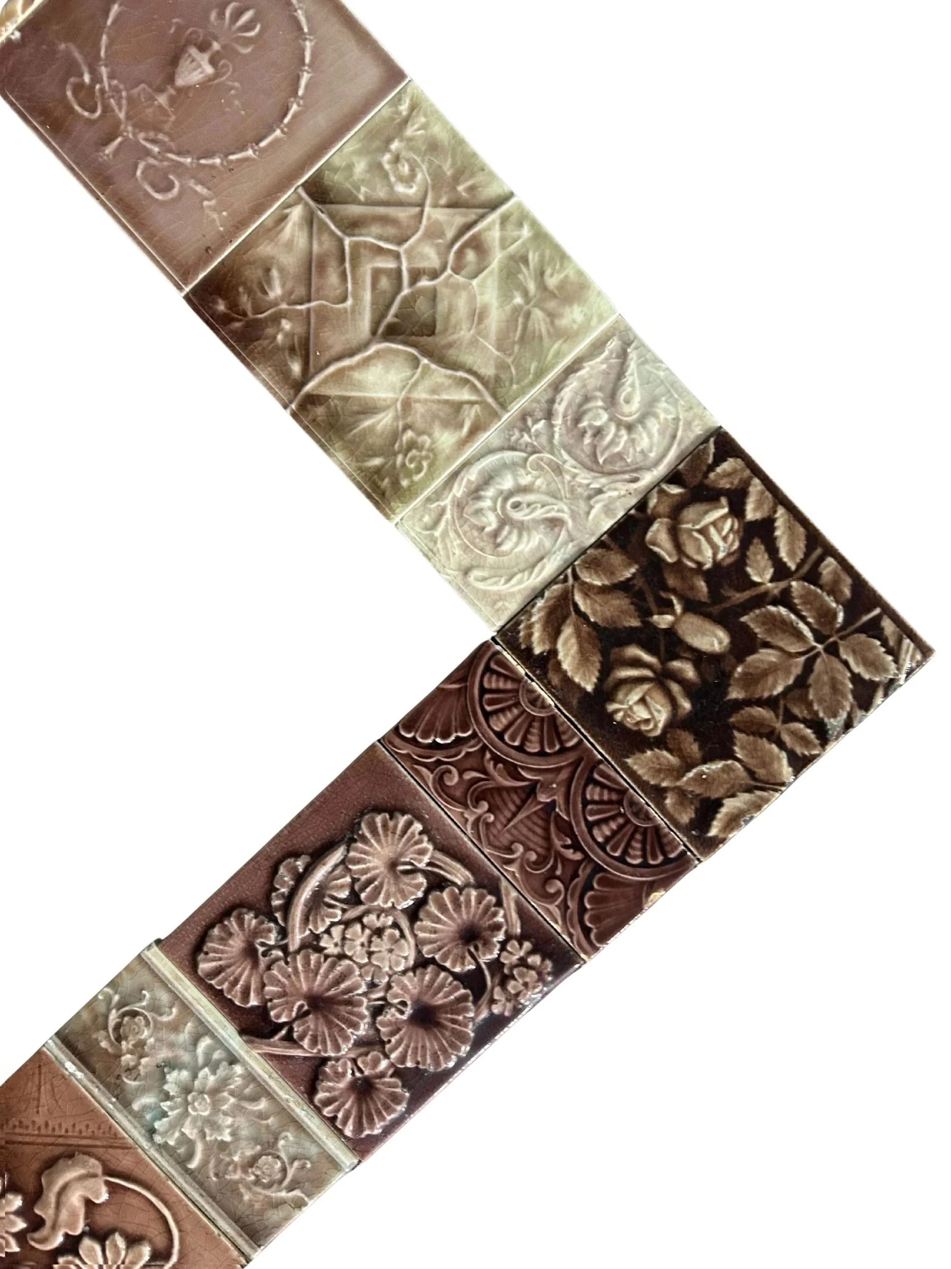 Antique Victorian tile fireplace surround featuring raised floral designs, swirling motifs, and warm brown, olive, and cream glazes.