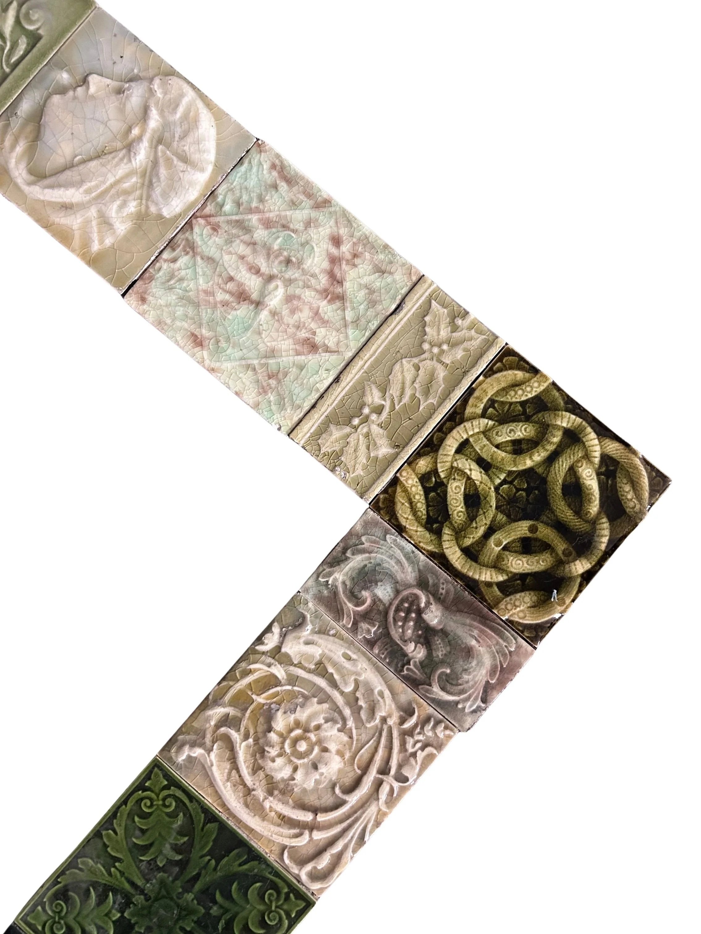 Antique Victorian decorative tile fireplace surround featuring intricate floral patterns, rich green glazes, and an eclectic mix of historic tiles.