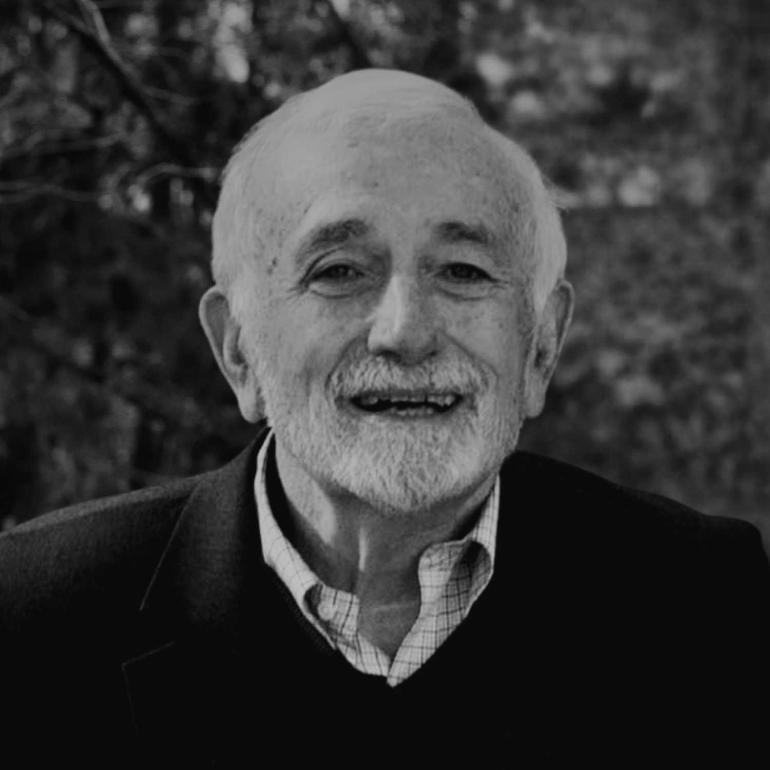 A group of professionally dressed men outdoors, including an older man with white hair and a beard smiling at the camera.