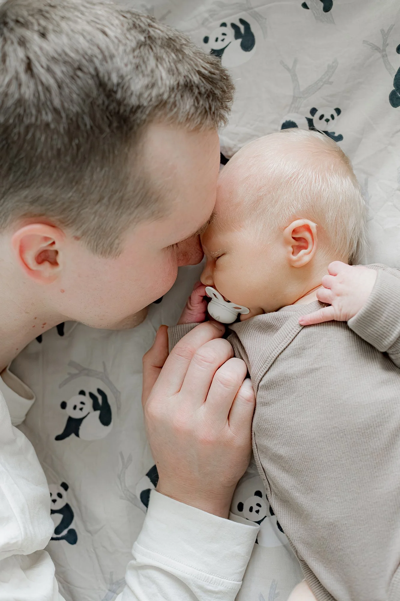 Isä pitää rakastuneena lähellään pientä vastasyntynyttä poikaansa. 