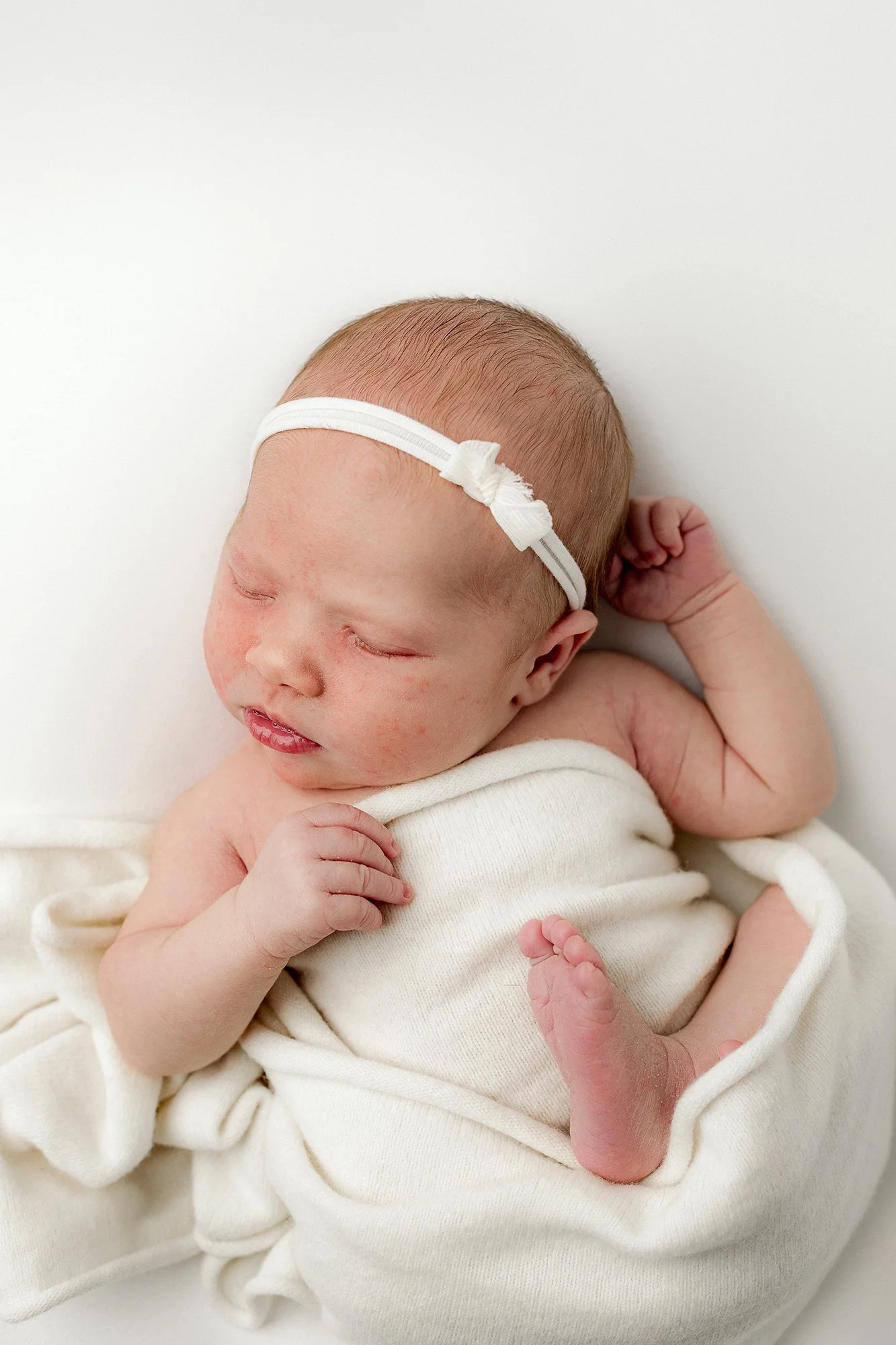 Newborn kuvaus studiolla Kouvolassa, äiti pitää kapaloitua vauvaa sylissä.
