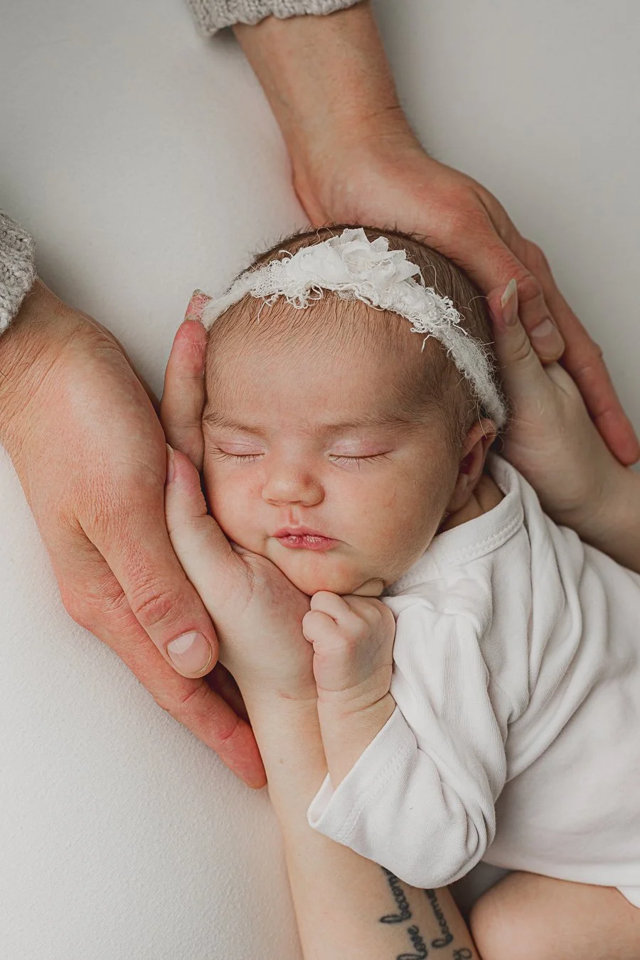 Vauva nukkumassa käärittynä valkoiseen kapaloon, pään päällä valkoinen pääpanta.