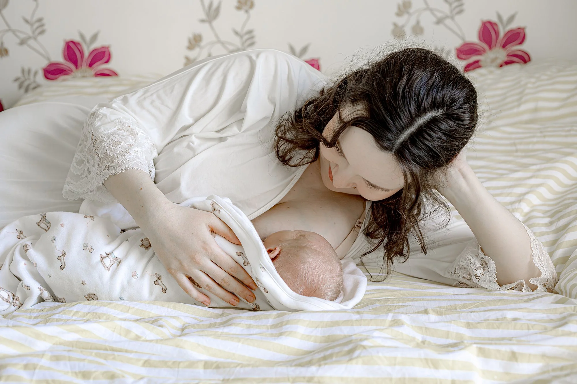 Äiti pitää lähellään pientä vastasyntynyttä, makoilevat vuoteessa.