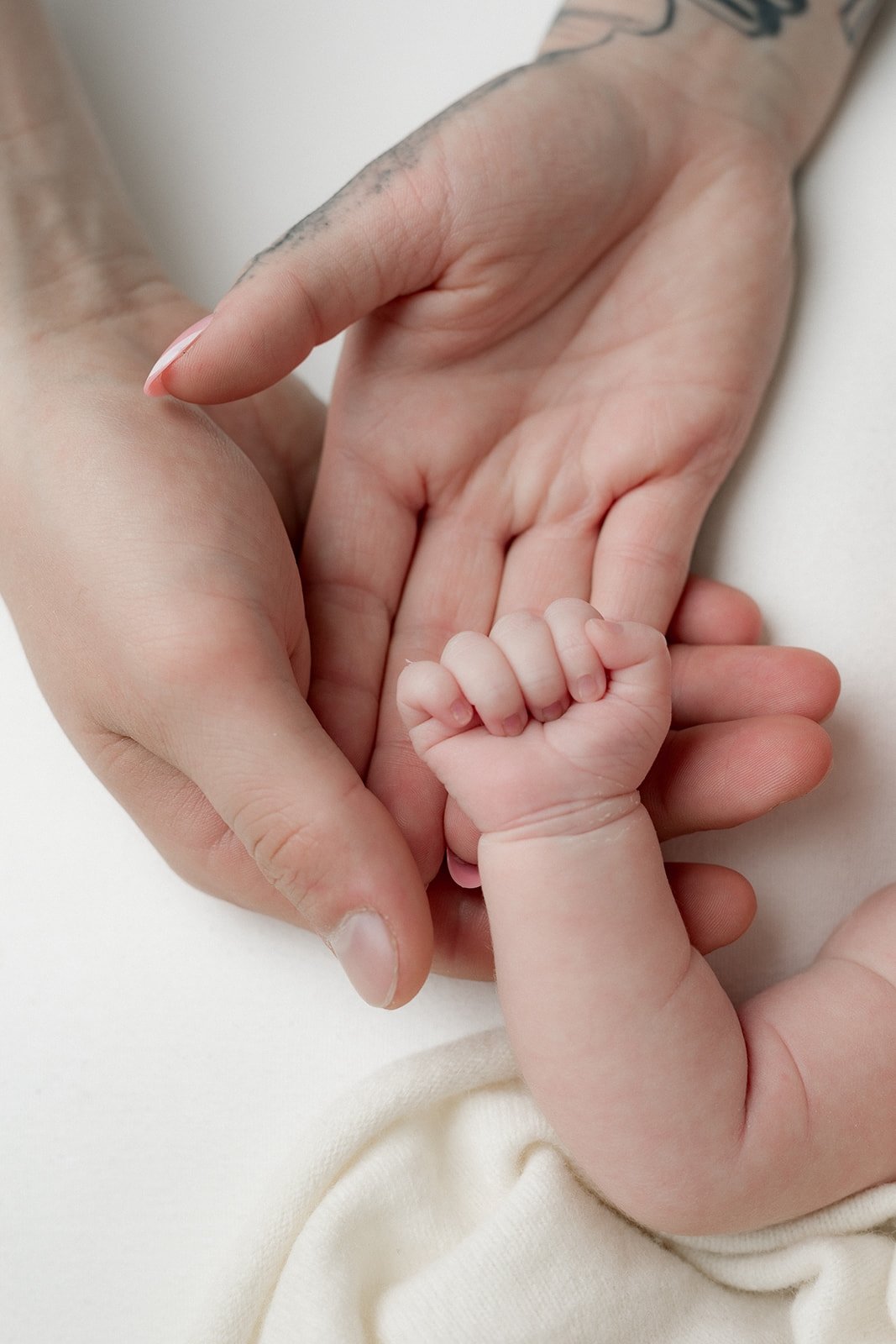 Kuvassa vastasyntyneen vauvan käsi, ympärillä äidin ja isän kädet. Newbornkuvauksessa Studio Susannamariassa Kouvolassa