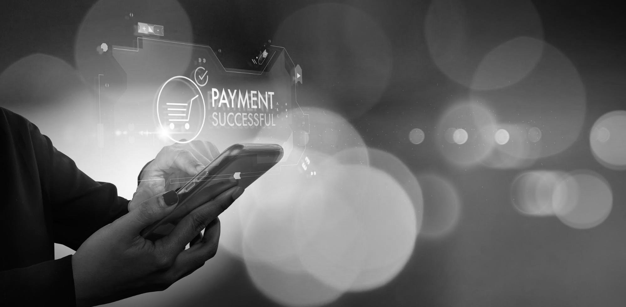 A person holding a smartphone showing a digital payment successful screen with a shopping cart icon.