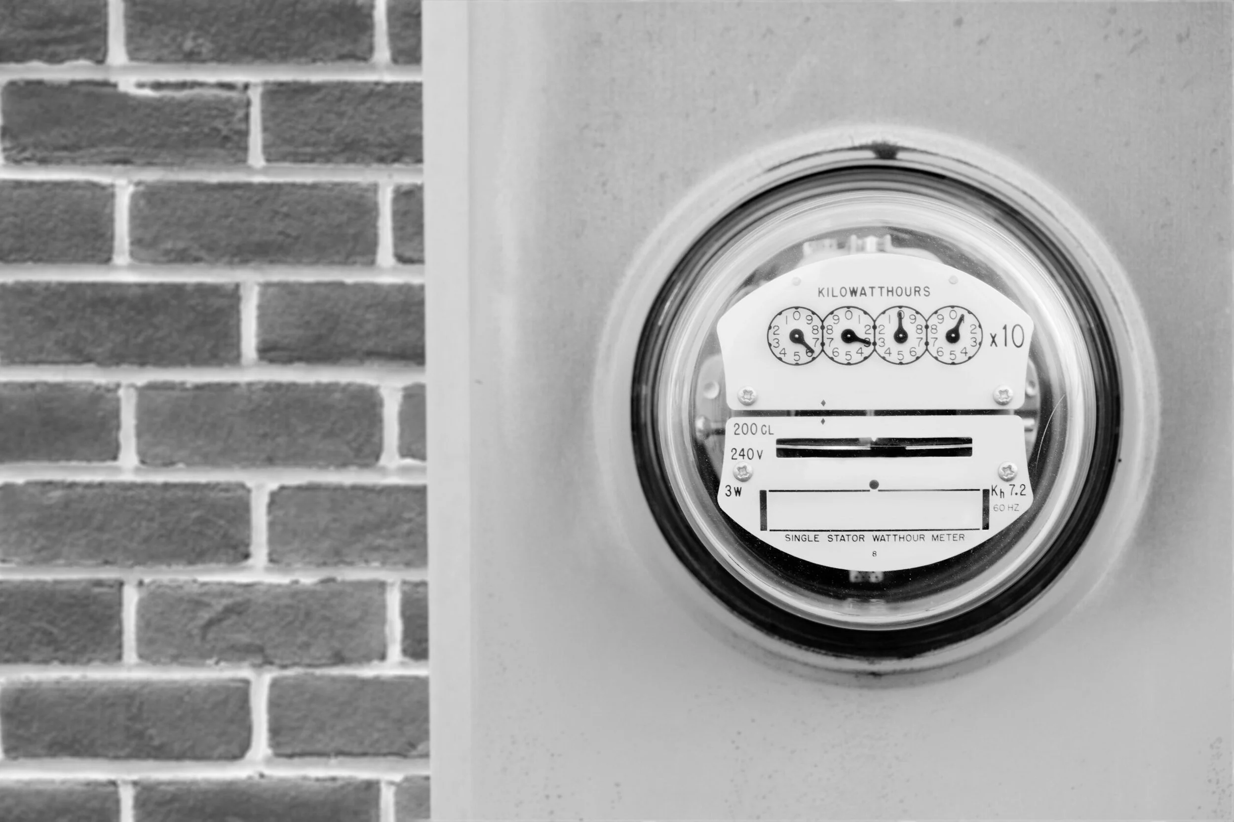 Electricity meter on a wall with a brick background to the left.