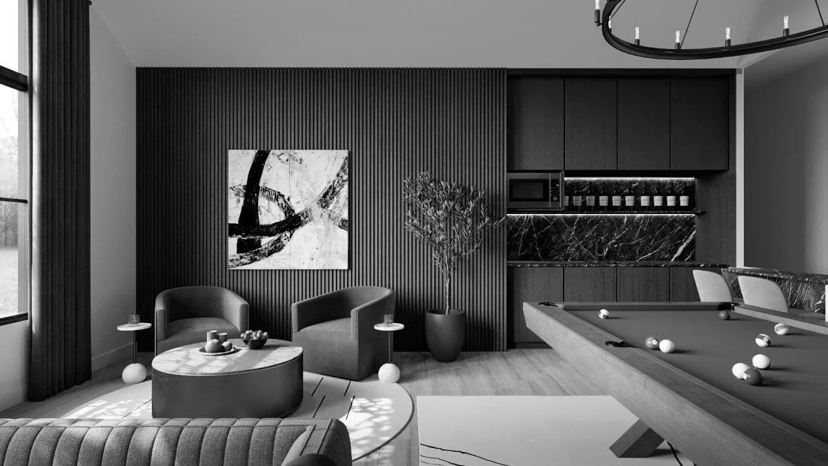 Modern living room with a pool table, two armchairs, a potted plant, abstract artwork, and built-in kitchen cabinets.
