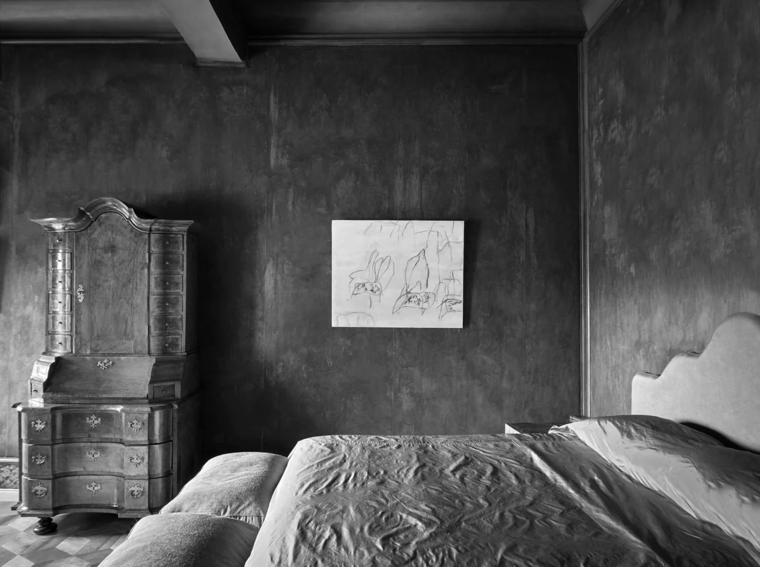 A bedroom with a large bed, an ornate wooden dresser, a chair, and a painting of flowers on the wall.