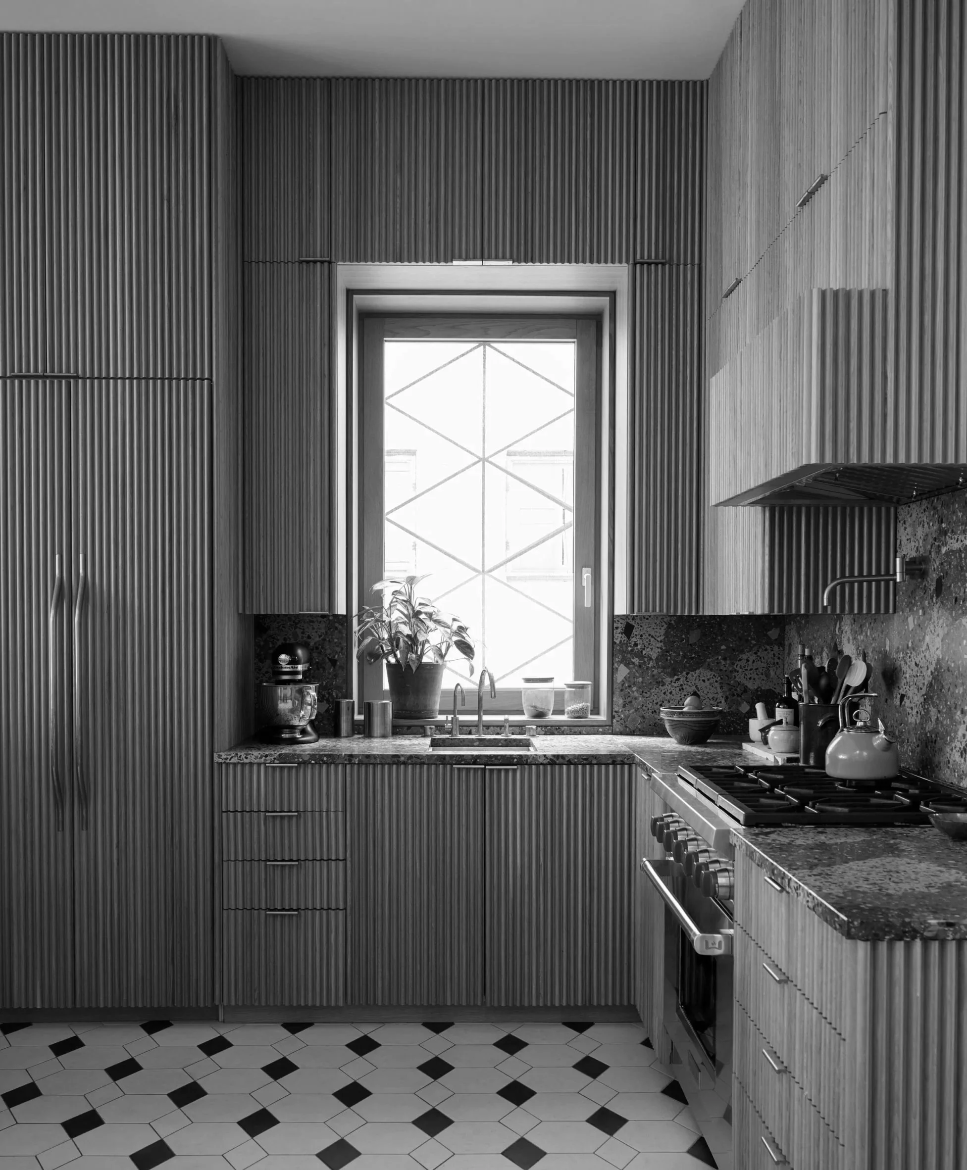 Modern kitchen with built-in cabinetry, a window above the sink, and various kitchen utensils and appliances on the countertop.