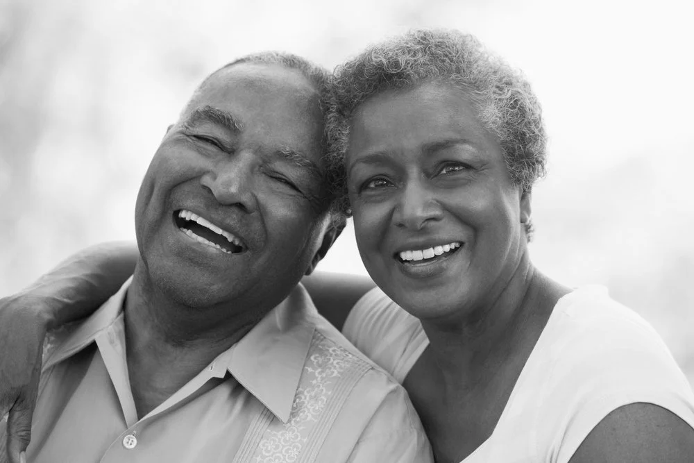 Black couple smiling and embracing each other outdoors.