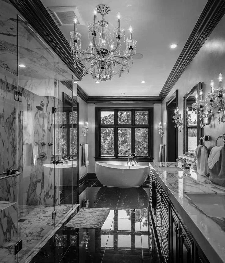 Luxurious bathroom with a chandelier, a freestanding bathtub by a large window, a marble shower area, and dark wood cabinetry.