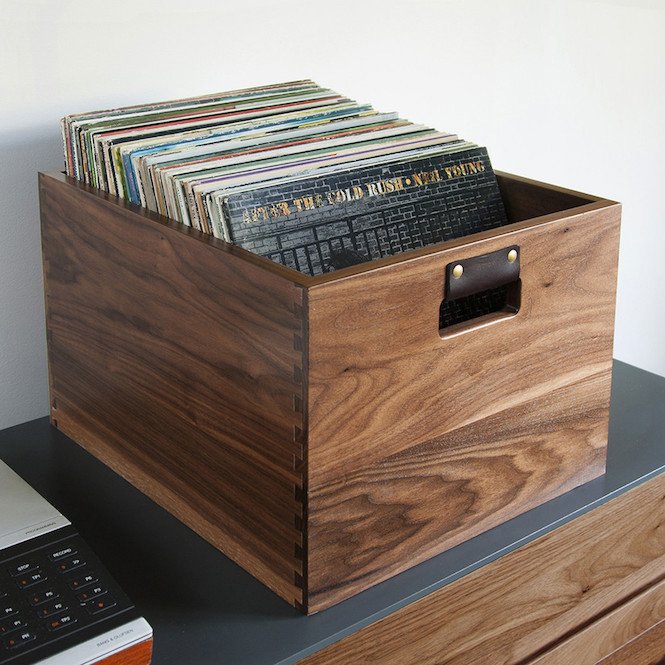 Wooden box filled with vinyl records on a gray surface.