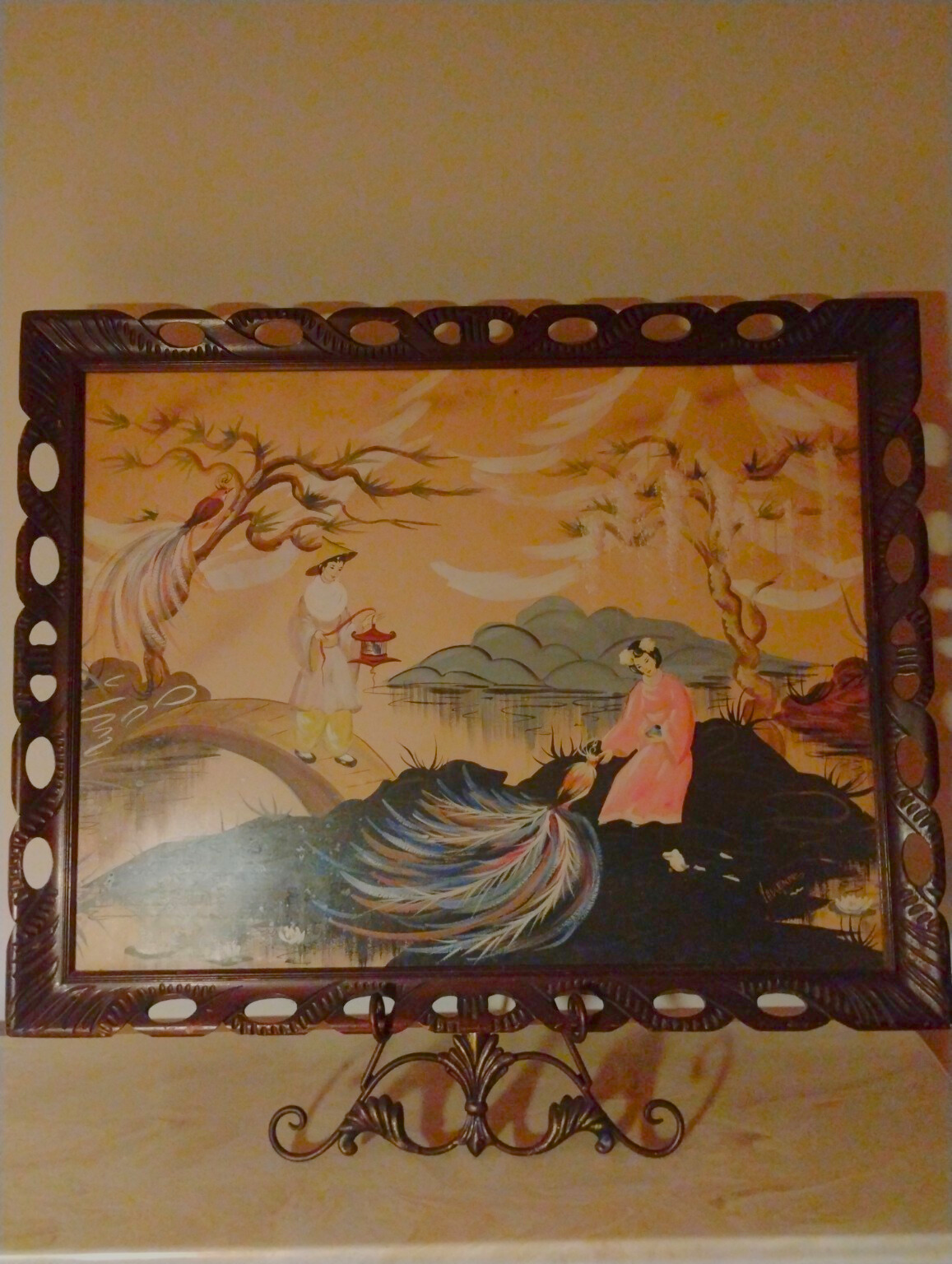 Mid-century Asian-style reverse glass painting depicting two women near a river — vintage oriental wall art from the 1940s, framed with warm orange and gold hues.