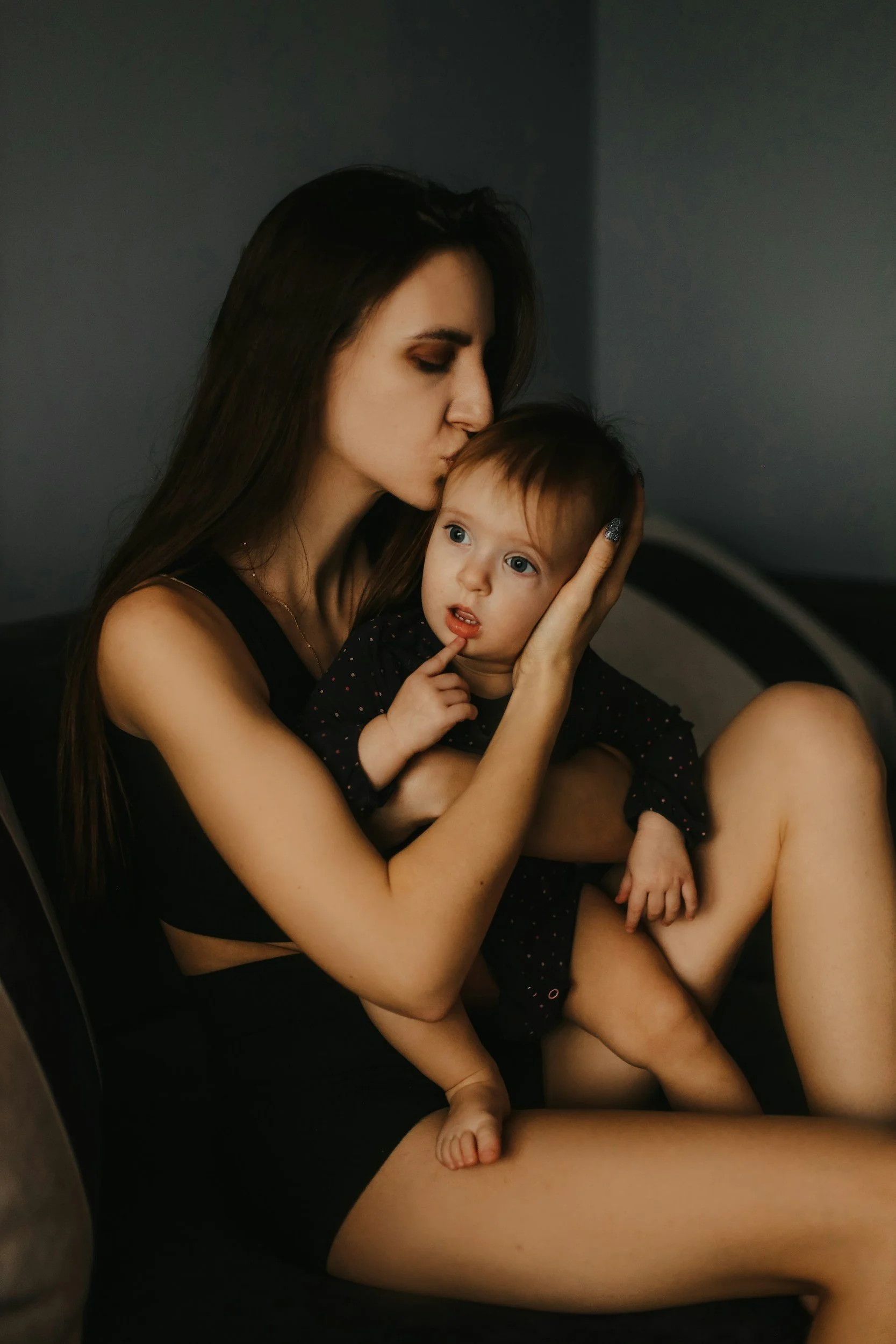new mom with postpartum depression holding baby in dark room