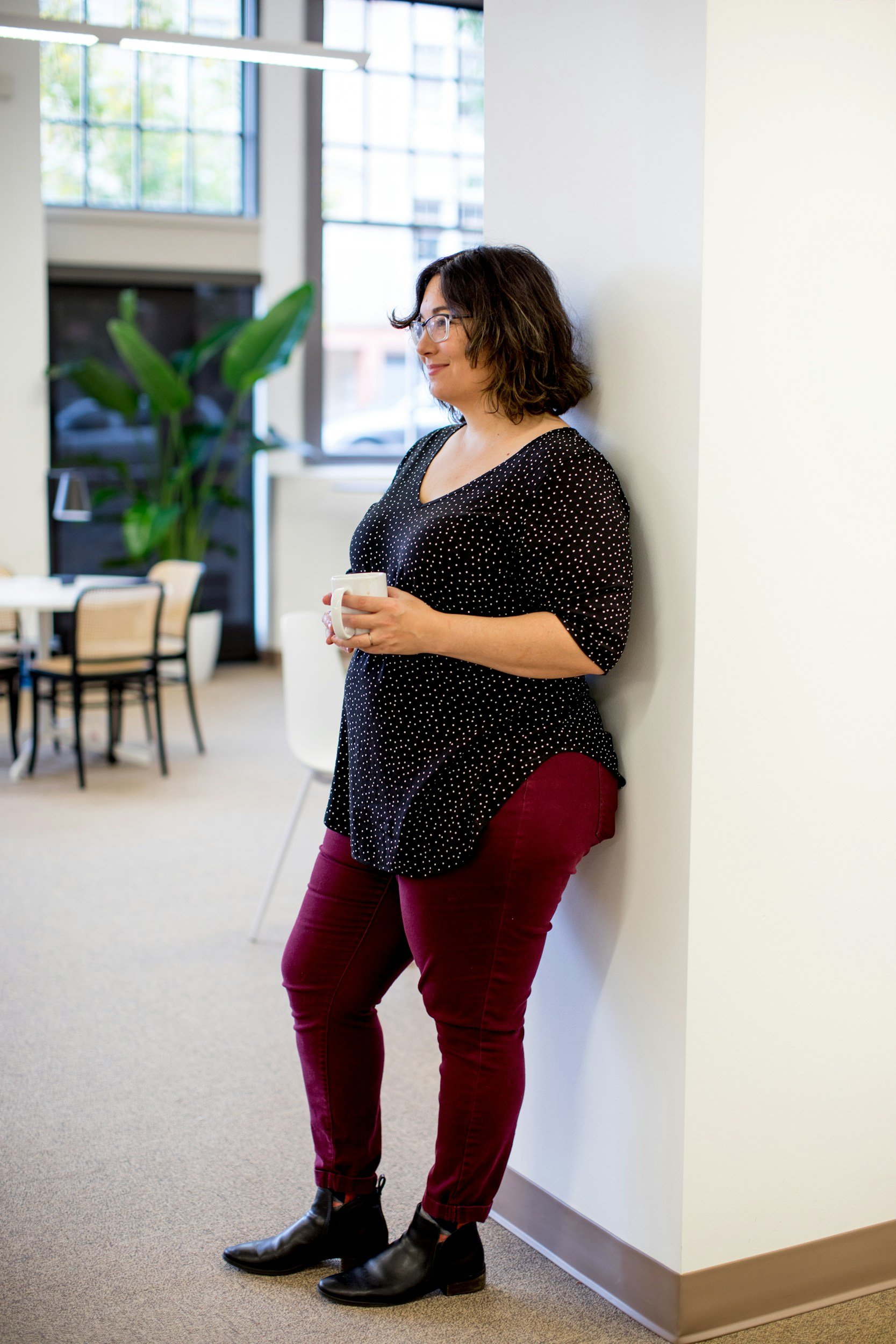 woman standing against wall smiling knowing her weight gain is due to perimenopause and can be addressed