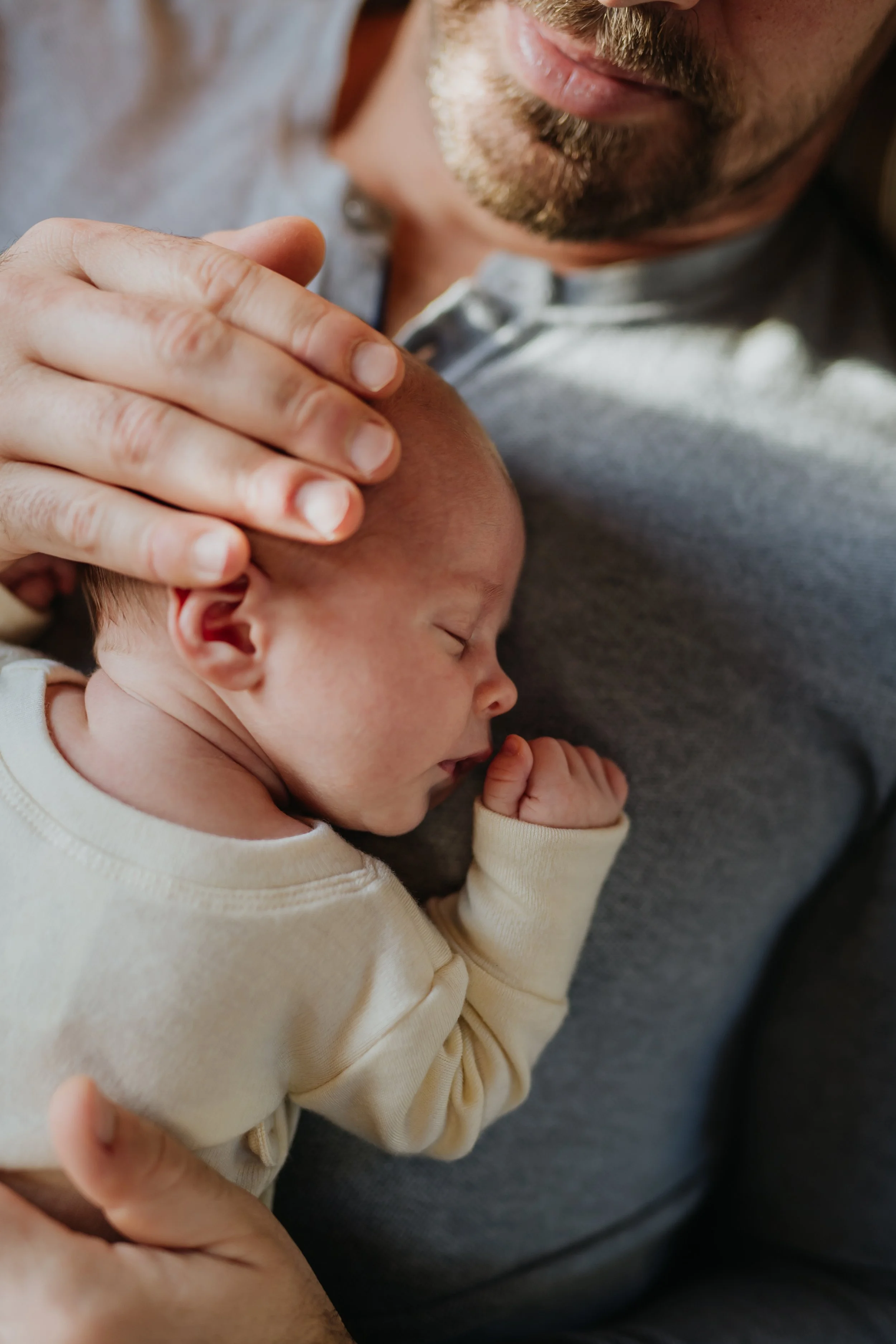 new dad laying on couch with newborn on his chest