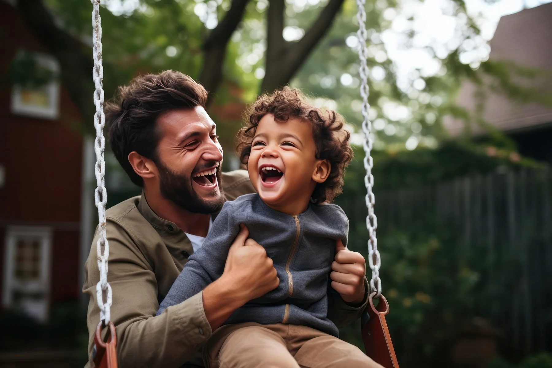 dad laughing while pushing son on swing
