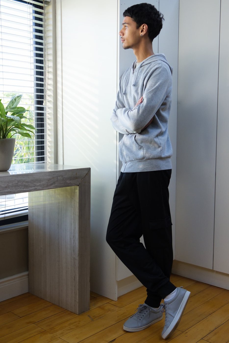 asian man staring out window feeling sad because he needs therapy to address his trauma