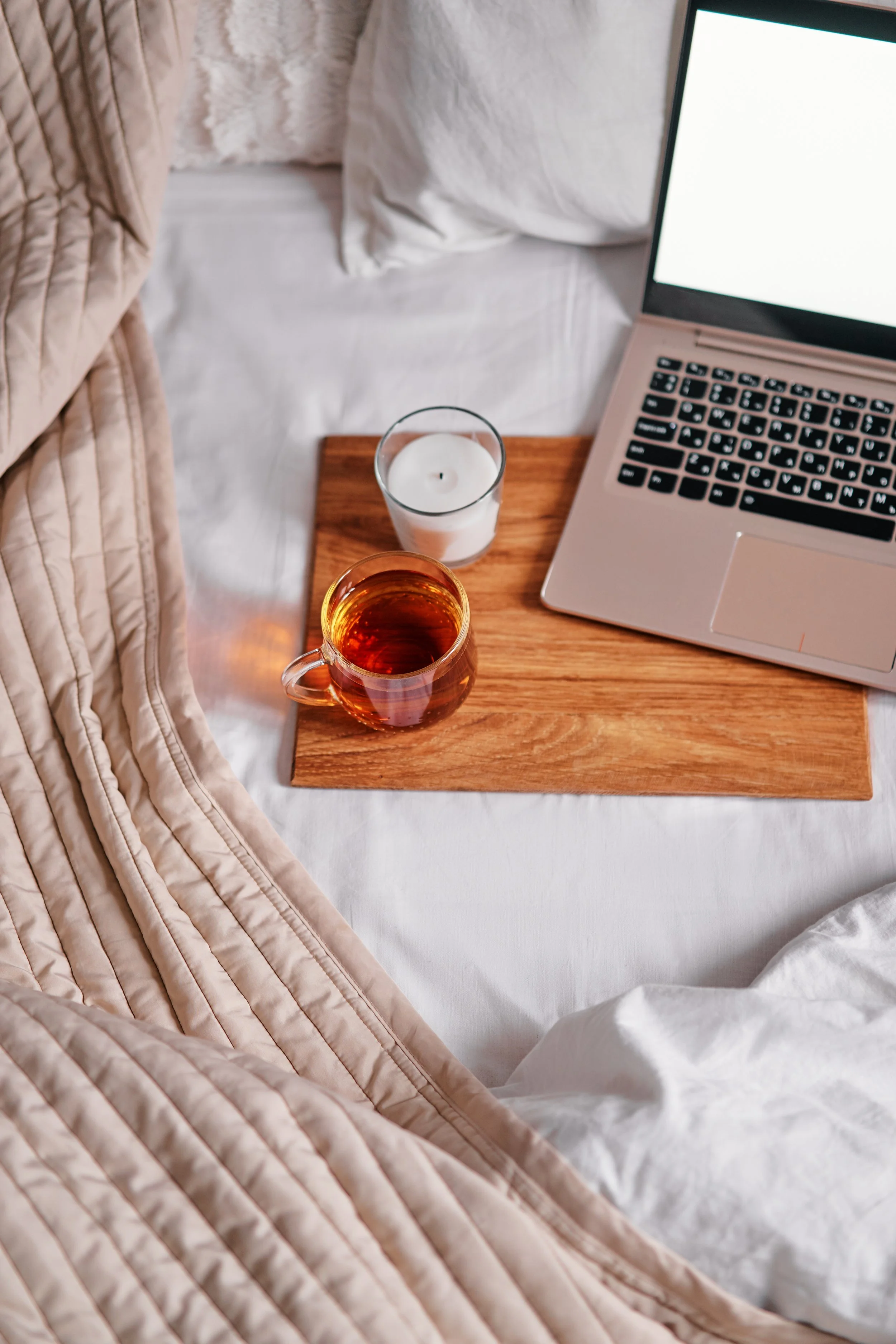Trauma therapy in the bed on laptop computer with wooden tray with cup of tea, trauma therapy near me