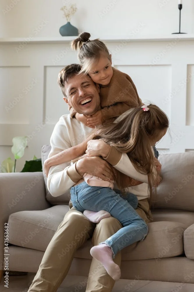 daughters hugging their dad while playing games together without screens, going analog