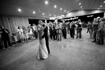 Couple dancing in a large room with guests watching, black and white photo.