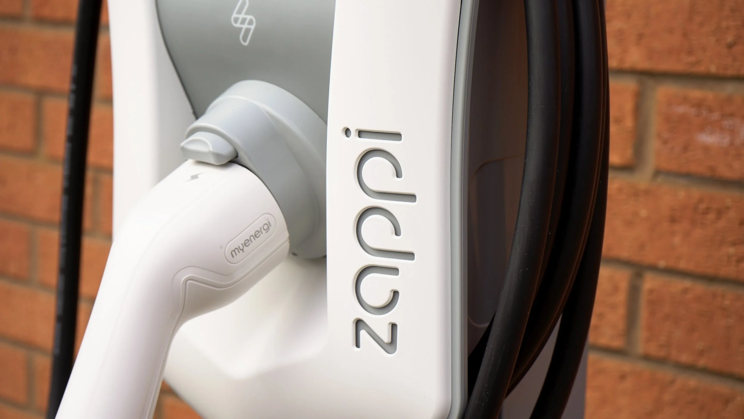 A Zappi EV charger installed at a brick wall of a home.