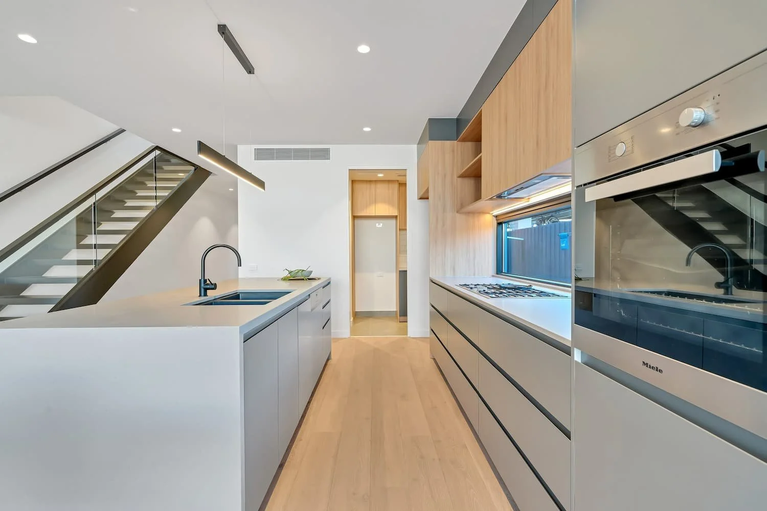 A modern kitchen with down lights and a pendant light, which can be installed by an Arconex electrician.