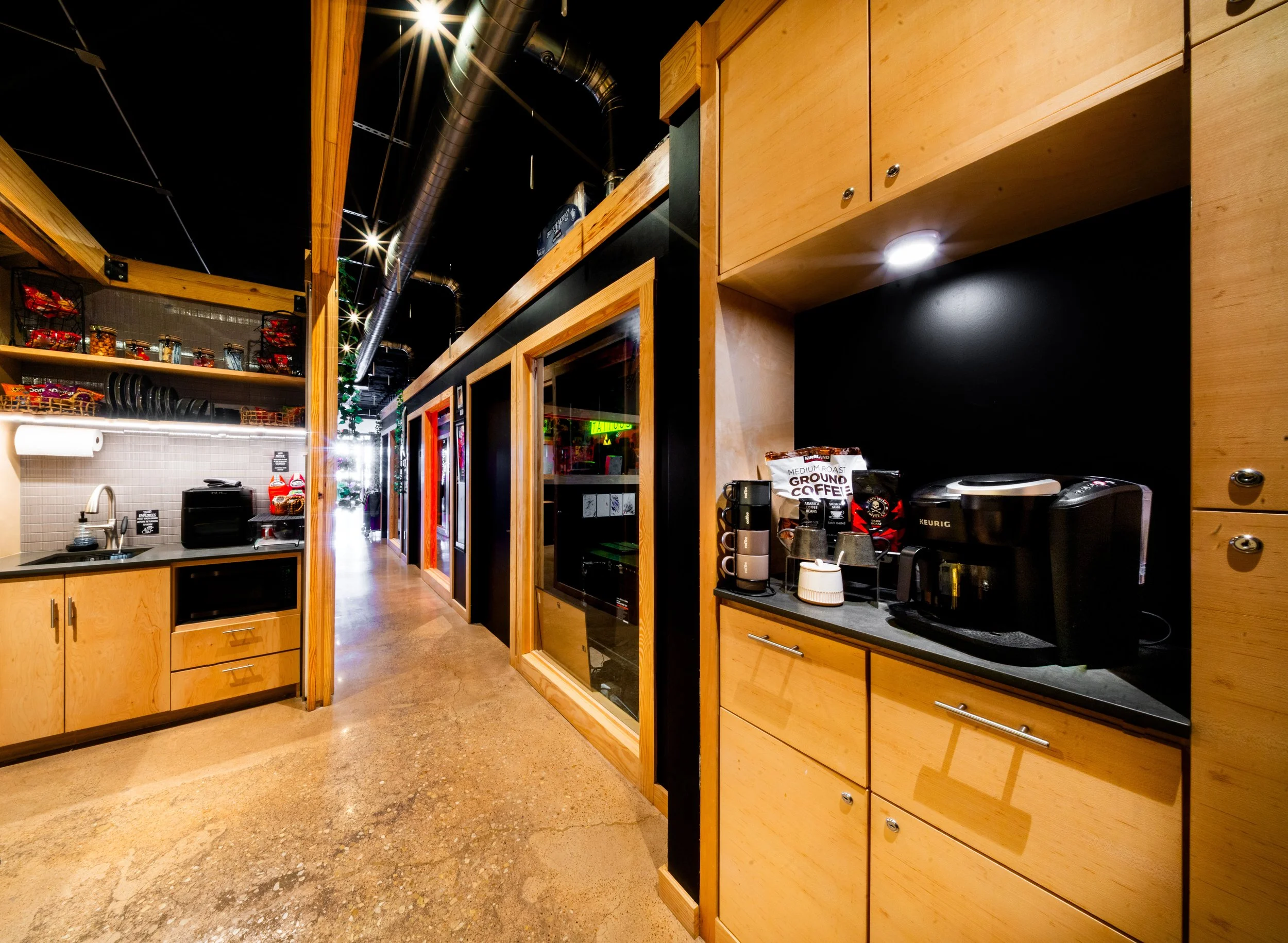 Modern kitchenette and hallway with private rooms at Cloak Collective, featuring amenities like a microwave, coffee station, and creative workspaces for artists in Duncanville, TX.