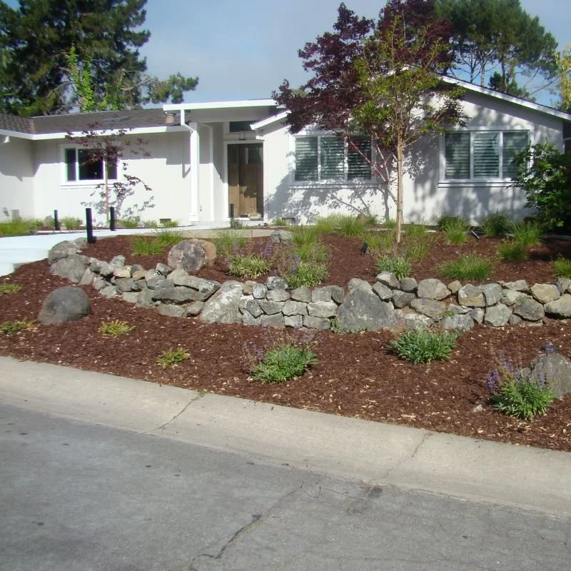 a stone retaining wall holding a garden