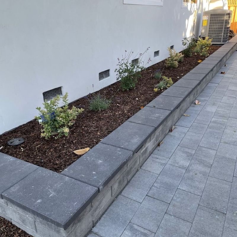 a stone retaining wall holding a garden bed