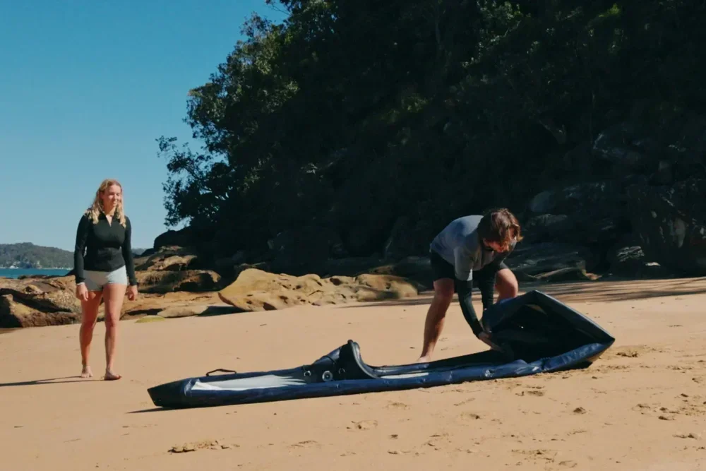 Zwei Personen beim Vorbereiten eines Razor Kayaks Edge Pro 2 Schlauchkajaks an einem Sandstrand.
