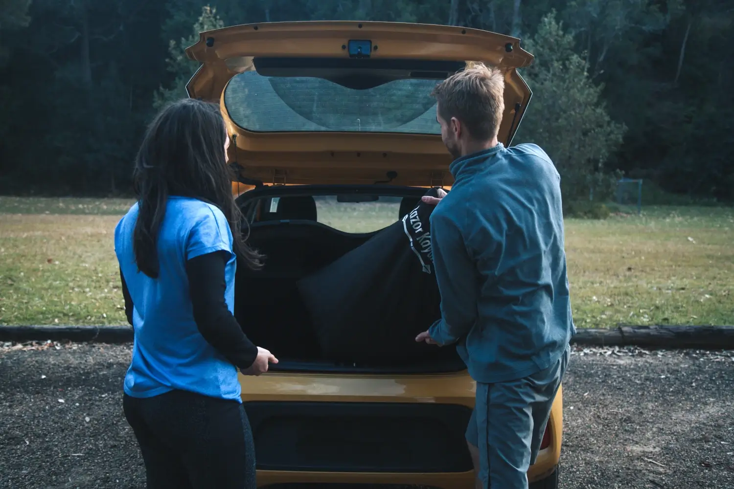 Una donna e un uomo che tirano fuori una borsa dal bagagliaio di un’auto