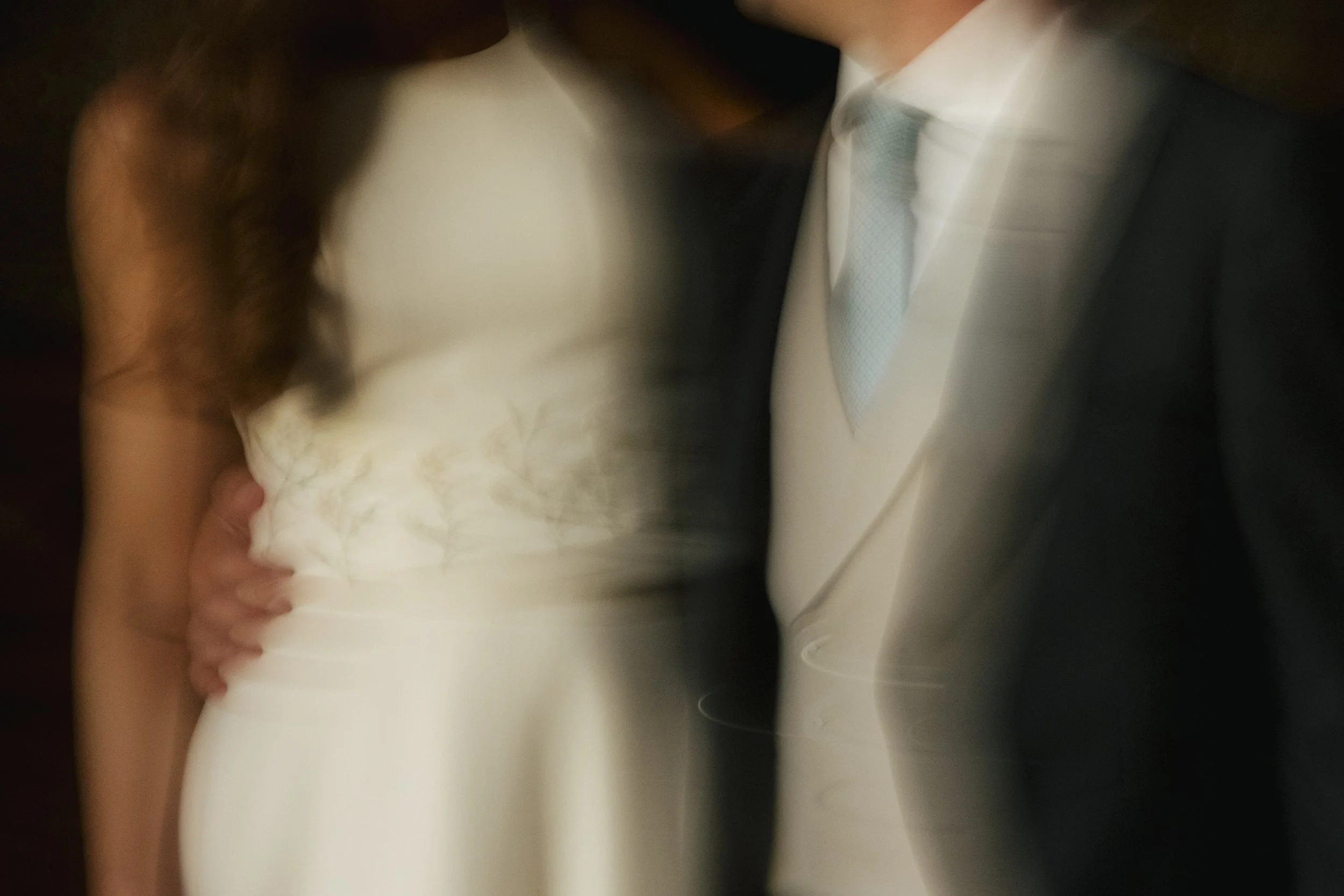 A couple dressed in formal attire, embracing each other at a wedding or special event.
