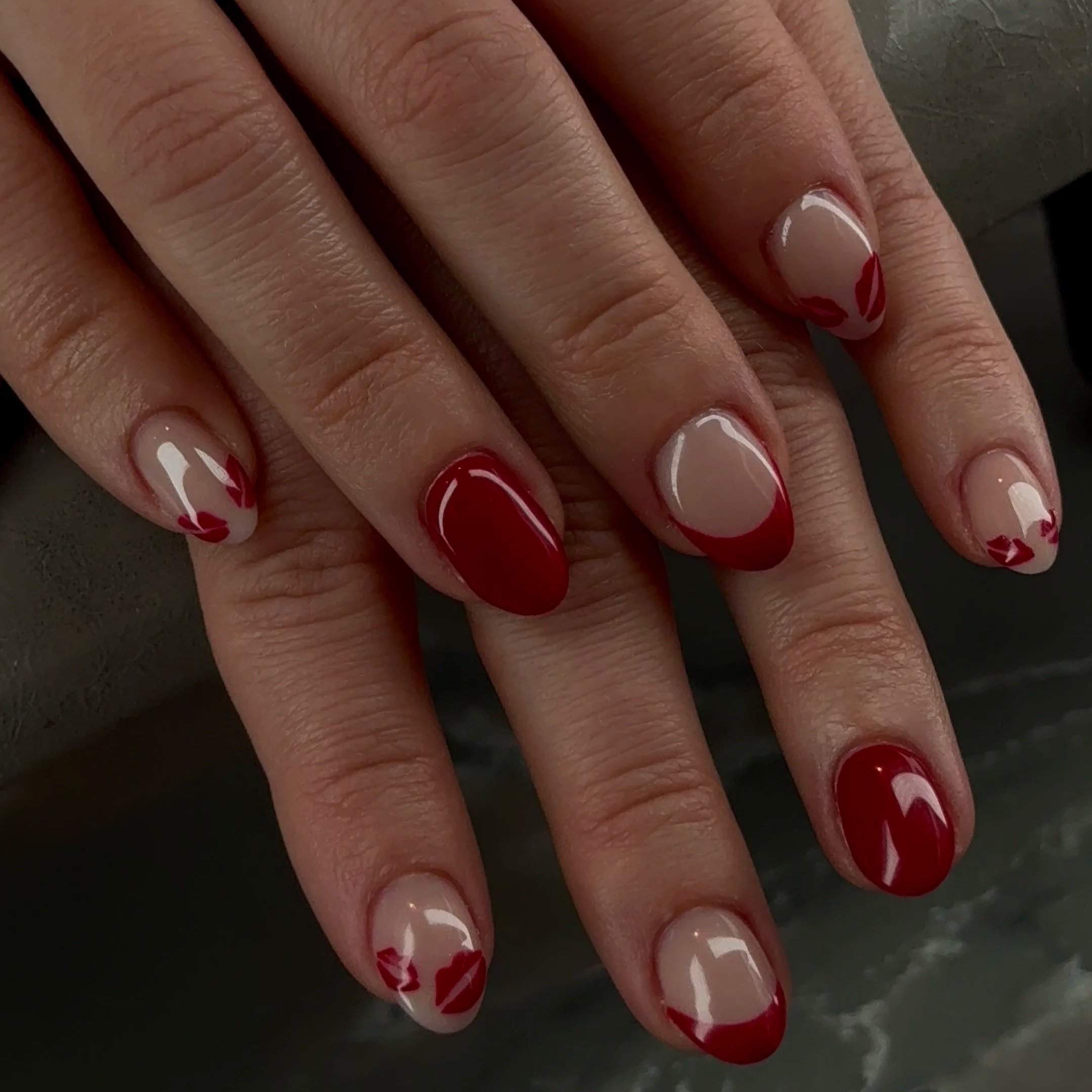 Close-up of a hand with decorated nails featuring red and white floral designs.