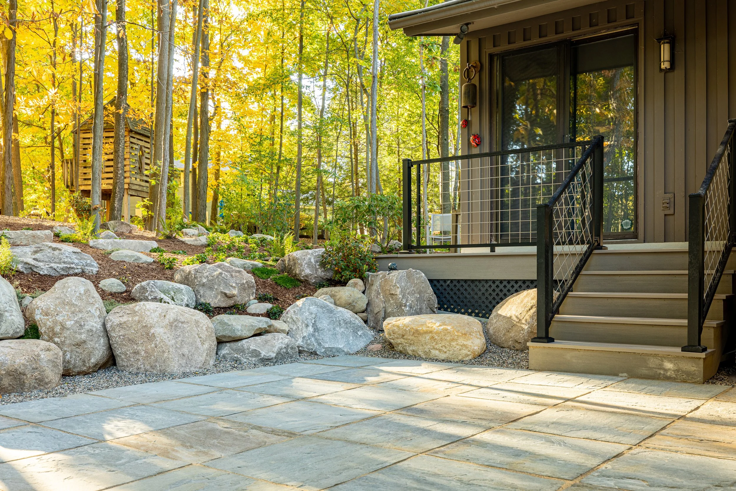 Custom patio with boulders and deck stairs