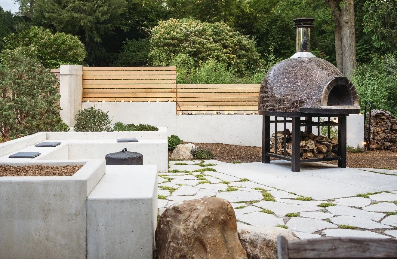 Custom patio with pizza oven, seating, and privacy wall