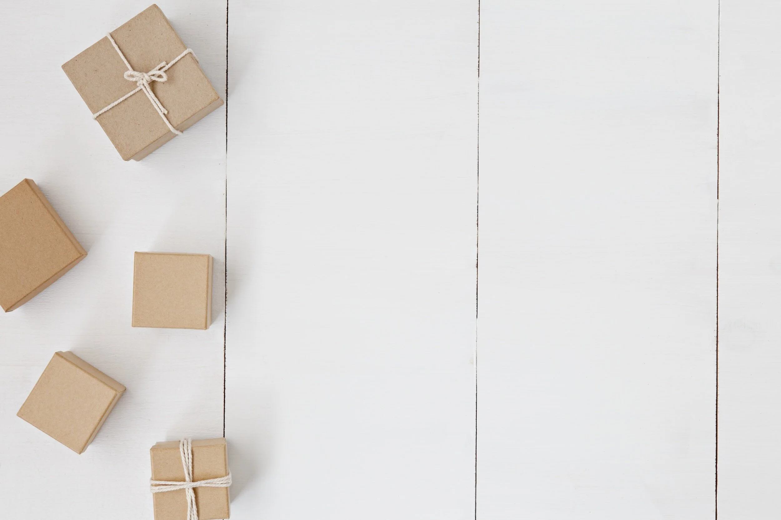 Five small brown gift boxes on a white wooden surface.