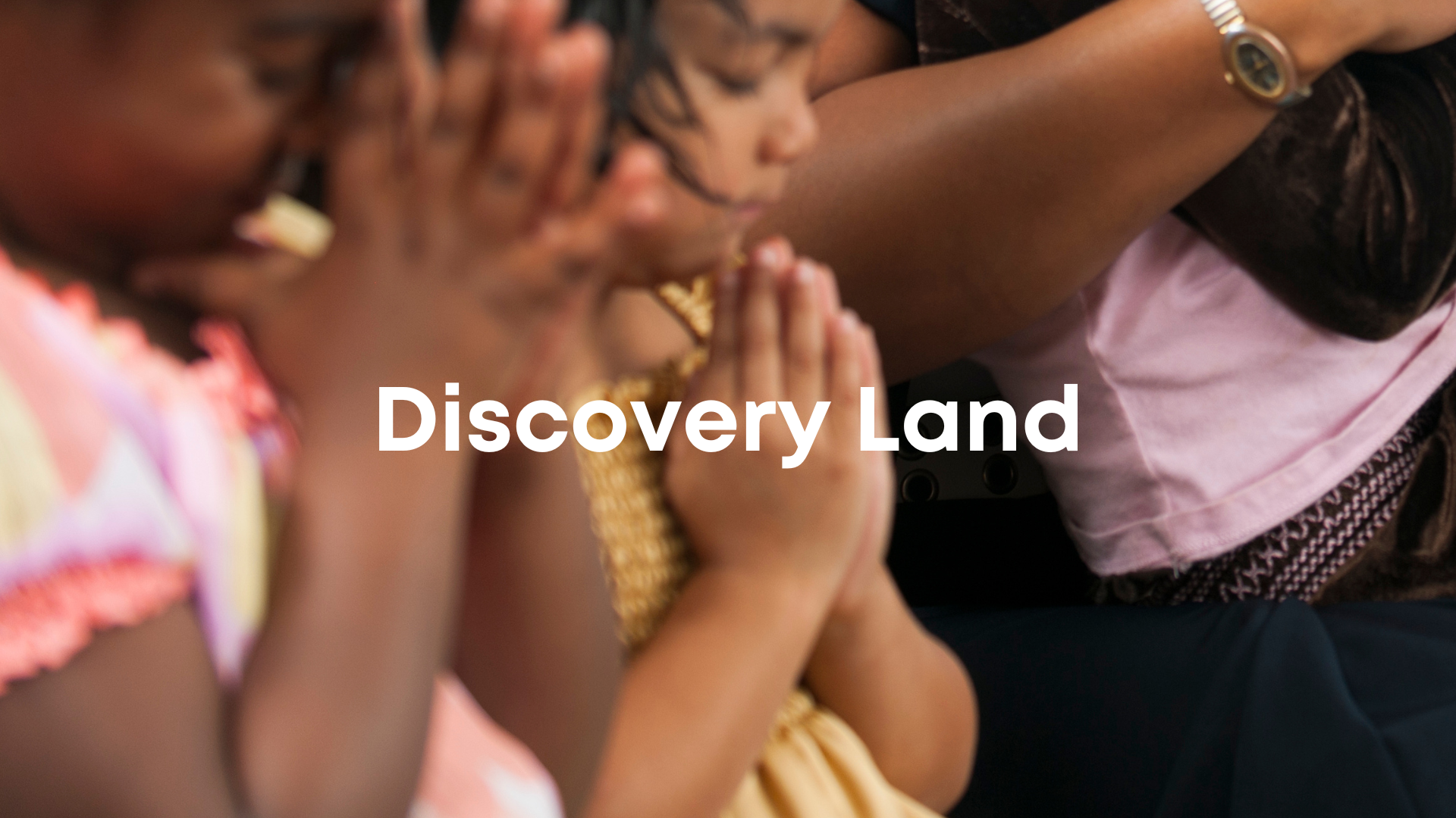 Children praying with hands clasped, paying homage in a spiritual setting, with the text 'Discovery Land' overlayed.