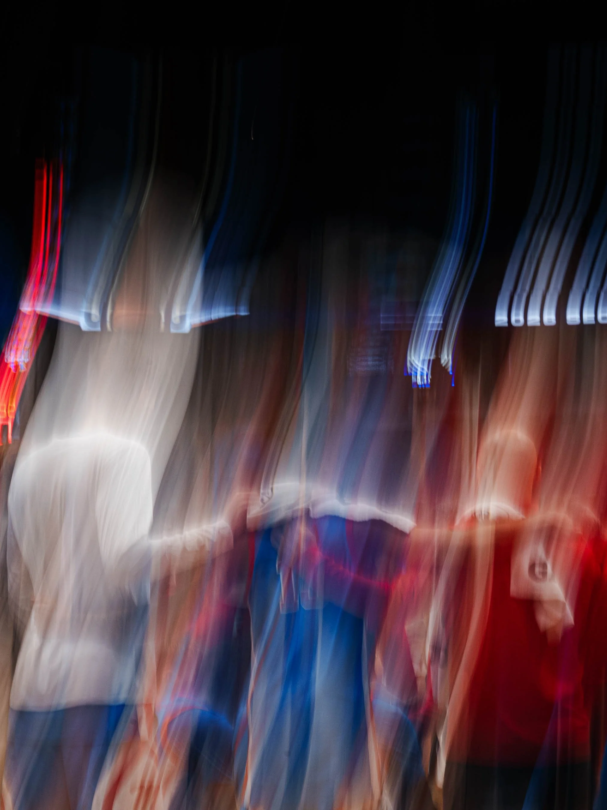 Blurred image of bright lights and signs at night, making it difficult to identify specific objects or locations.