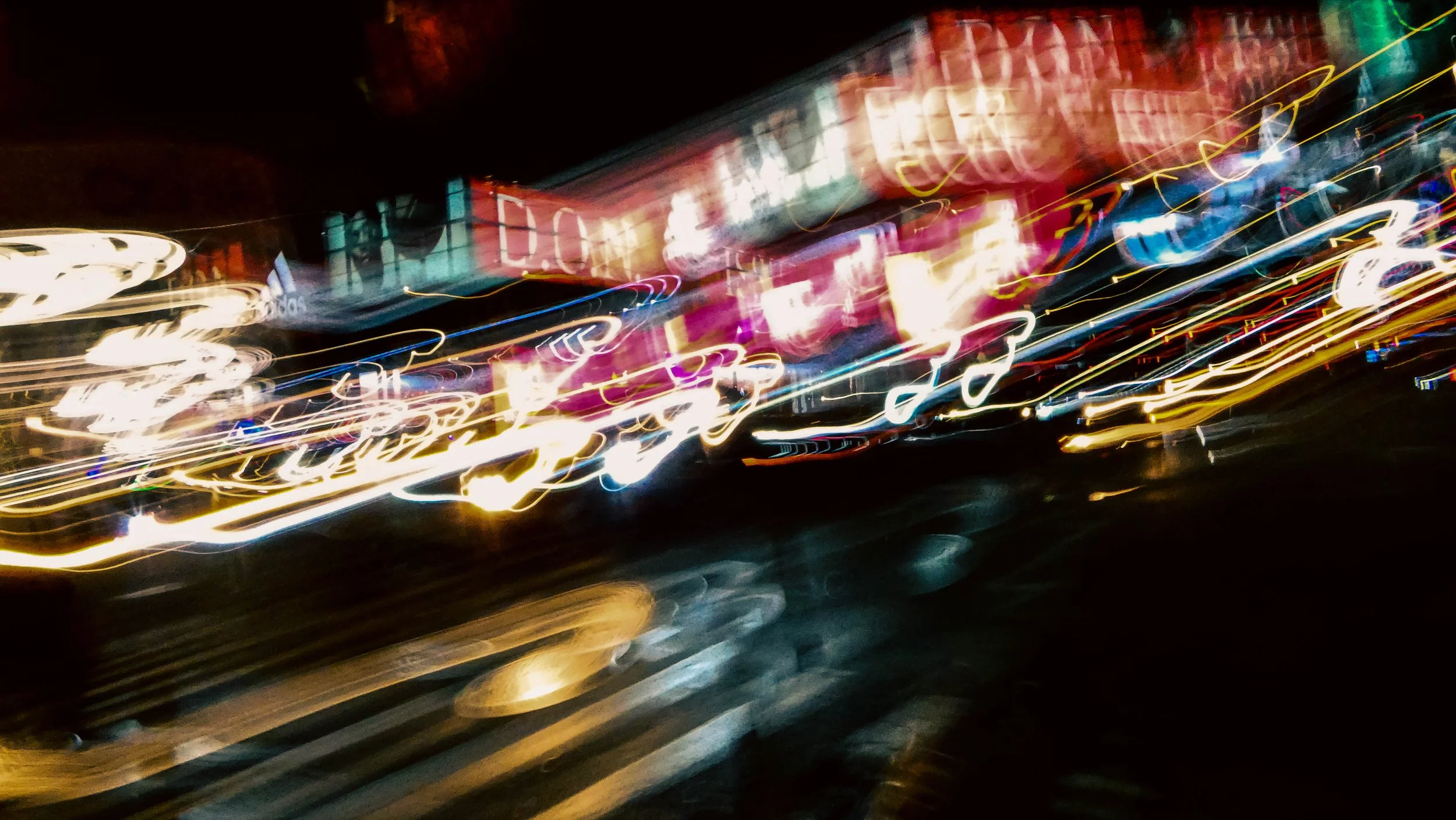 Bright, colorful city lights at night with motion blur creating streaks of light and abstract patterns.
